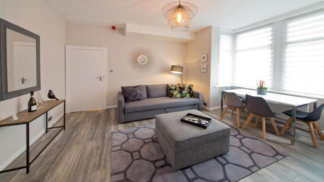 Lounge pictured from bedroom showing console table, sofa, dining table and large footstool